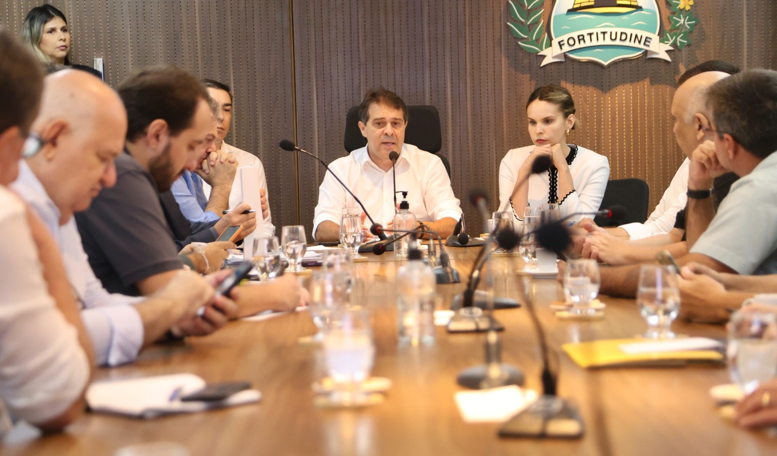 prefeito na mesa de reunião, acompanhado por secretários